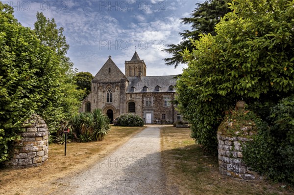 Historic church with a path surrounded by green trees and blooming nature, The Abbey de La Lucerne