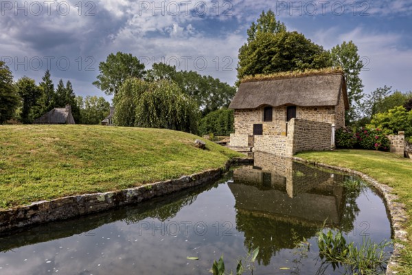 Small house with thatched roof in a quiet, green setting by a stream, The Abbey of La Lucerne in