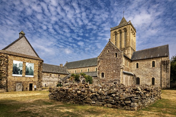 A church with adjoining ruins and stone walls under a blue sky, The Abbey de La Lucerne in