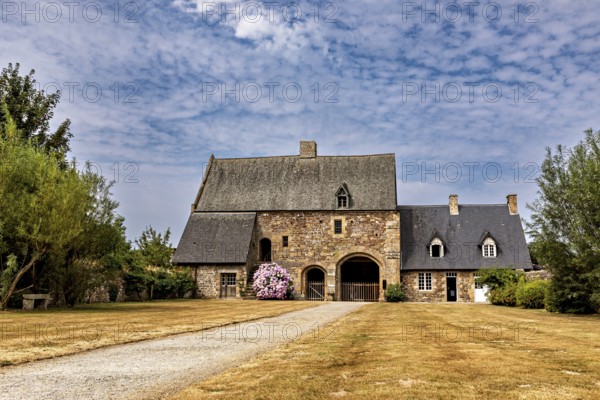 An old stone house with a gravelled path and a blue sky, surrounded by manicured lawns, The Abbey