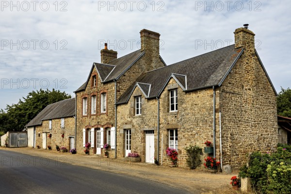 Historic stone houses along a village street with flowering windows, Historic houses in Normandy in