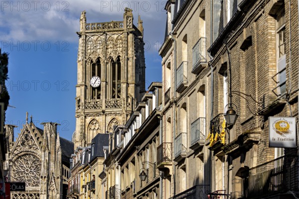 Gothic cathedral with impressive bell tower and stone architecture along the street under a blue