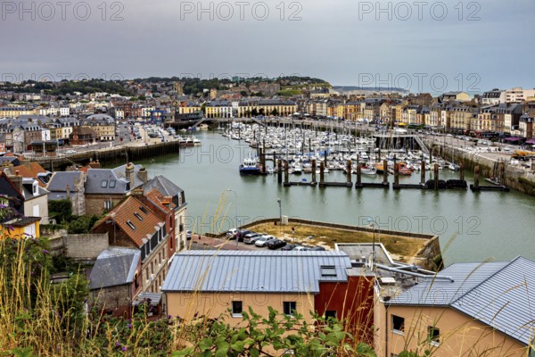 View of a busy harbour town with many boats and city buildings under a cloudy sky, The harbour of