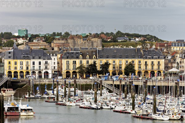 Yellow historic buildings overlook a busy harbour with many boats, The harbour of Dieppe in
