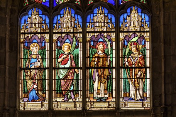 A Gothic church window shows colourful depictions of angels and saints in detailed stained glass,