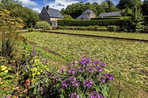 Lush flower bed in front of a charming brick house in a summery, rural setting, The historic mill