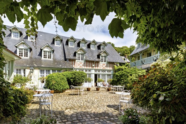 Inviting courtyard with cobblestones, garden furniture and a charming half-timbered house, The
