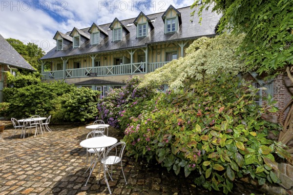 Lively garden with flowers and seating areas, surrounded by a backdrop of half-timbered houses, the