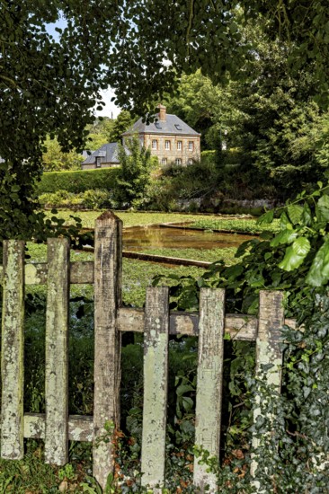 A cosy house behind an old, overgrown garden fence in a rural setting, the historic mill village of