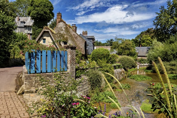 Thatched roof house with blue fence on a path surrounded by natural, picturesque landscape, The