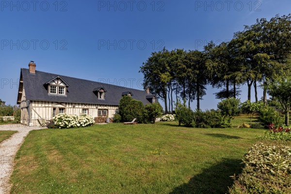 Inviting half-timbered house on a sunny day with a well-tended garden and stately trees, Historic