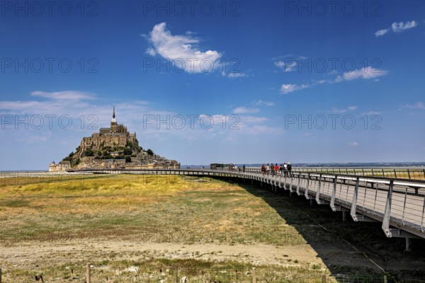 A medieval castle with a long wooden bridge under a clear blue sky, Mont Saint Michel in Normandy,