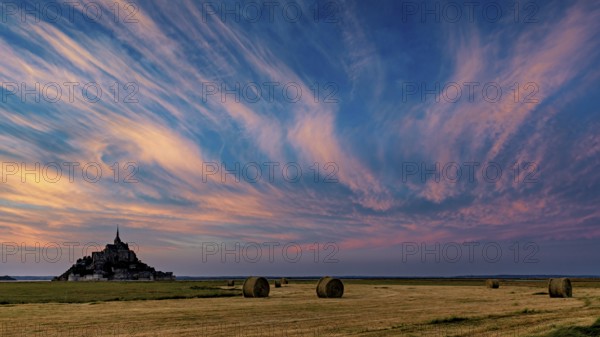 Mont Saint-Michel at sunset with dramatic sky and straw bales, Mont Saint Michel in Normandy,