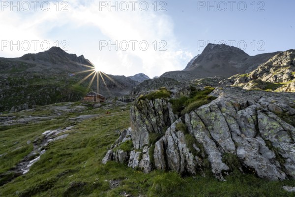 Mountain hut Elberfelderhütte in front of a rocky mountain landscape, sun star in the morning, in