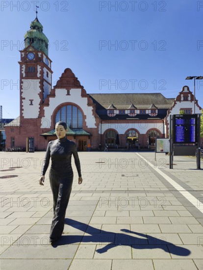Realistic artwork entitled Walking Woman by Sean Henry on the square in front of the railway