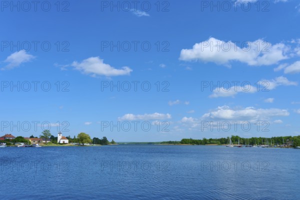 Lake with blue sky and clouds, in the background a village with a church, Rhodes, Etang du Stock,