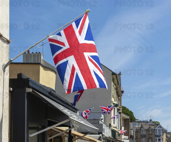 Union Jack flags on shops in street of historic buildings, The Strand, Dawlish, south Devon,