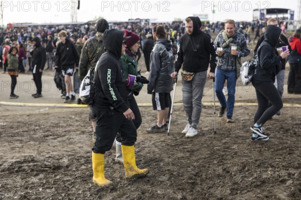 Festival visitors walk through mud in wellies at the Rock am Ring festival on Sunday, Nürburgring