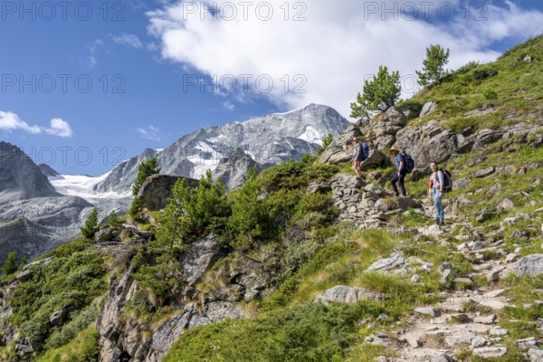 Three mountaineers on a hiking trail, mountain landscape near Arolla, behind mountain peak Mont