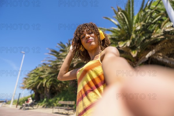 Tourist enjoying a sunny day on the beach, taking a cheerful selfie while listening to music