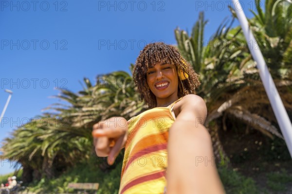 Carefree young woman with yellow headphones enjoying music, pointing finger and taking selfie in a