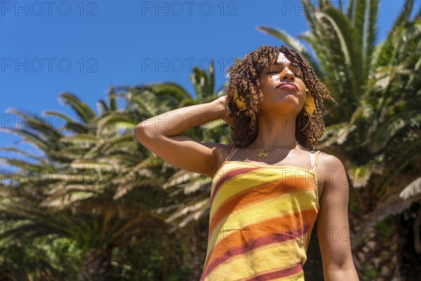Young woman enjoying music with headphones in a tropical location, embracing the summer vibes and