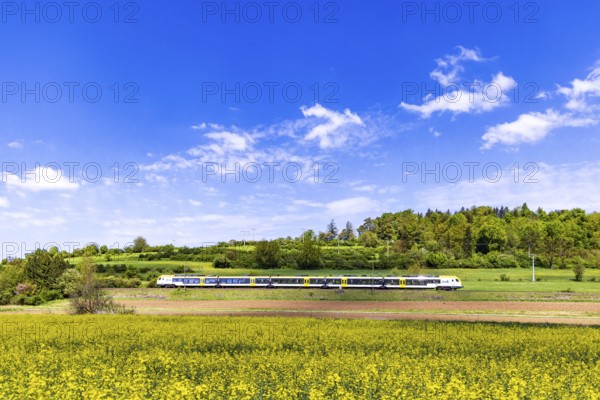 Regional train travelling on the Swabian Alb. Landscape on the railway line in spring. Lonsee,
