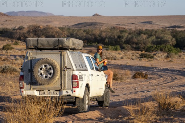 Tourist with off-road car on a sandy track, rock formation, Brandberg, Damaraland, Namibia