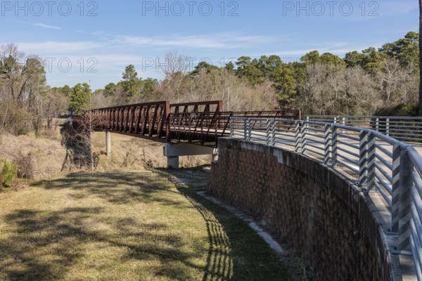 Steel bridge along paved biking and walking trail in Cypress Creek Park at Timber Lane in Spring,