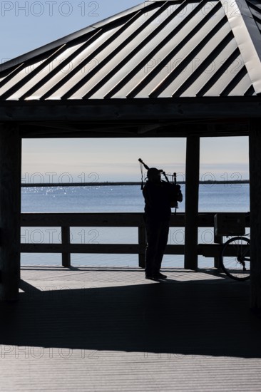 Silhouette of a man playing bag pipes under a pavilion on Halstead Bayou in Gulf Islands National