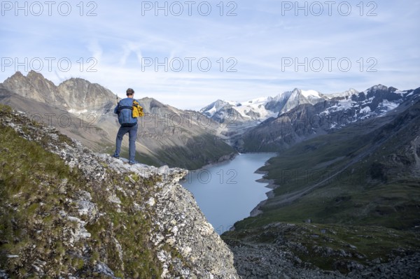 Mountaineer on the summit of Mont de la Blana, view of a blue mountain lake, Lac des Dix reservoir,