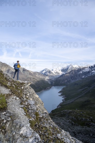 Mountaineer on the summit of Mont de la Blana, view of a blue mountain lake, Lac des Dix reservoir,