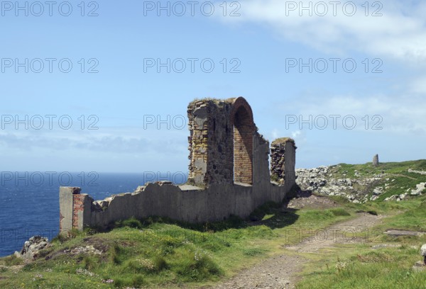 A coastal ruin with a view of the blue sea and green meadows under a cloudy sky, Mining, Botallack,