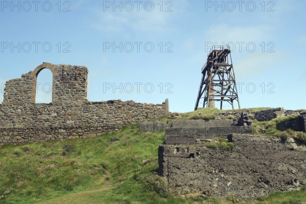 Mining ruins and a derelict tower stand on a grassy hill, engine room, mining, Botallack, Cornwall,