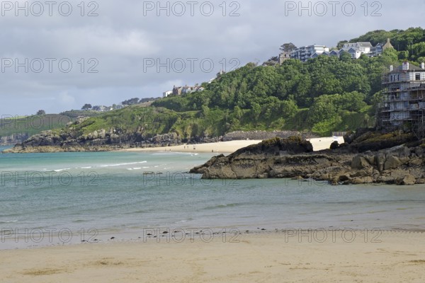 Sandy beach beach with sea view and hills covered with green trees and scattered houses, St Ives,
