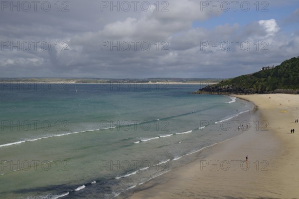 Spacious beach with gentle waves and few people under a cloudy sky, St Ives, Cornwall, England,