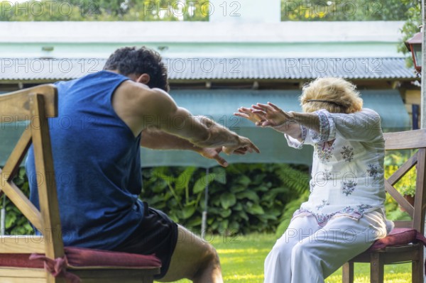 Physiotherapist assisting a senior woman with rehabilitation exercises in a vibrant home garden,