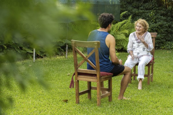 Young male nurse assisting an elderly woman during a home visit, engaging in conversation while