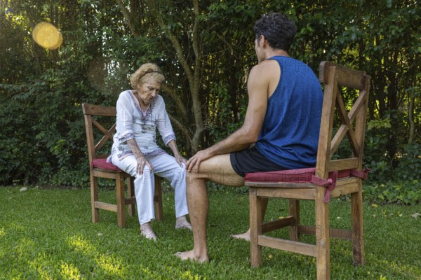 Senior woman experiencing knee pain receiving assistance from a physiotherapist during an outdoor