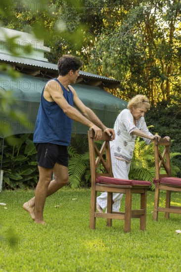Young male physiotherapist assisting a senior woman performing rehabilitation exercises using