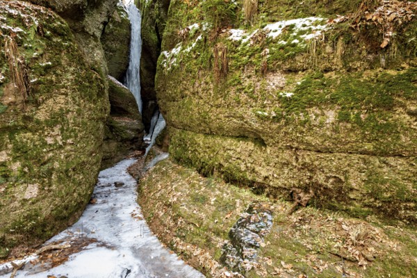 Narrow pass between moss-covered rocks with dammed ice and snow-covered ground, the Dragon Gorge