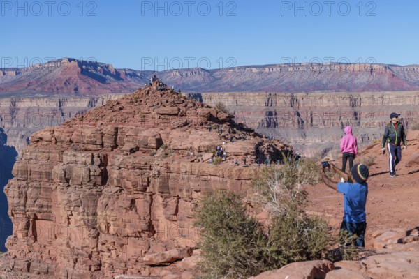 Visitors climb on rock formation rising above the canyon at Guano Point in Grand Canyon West near