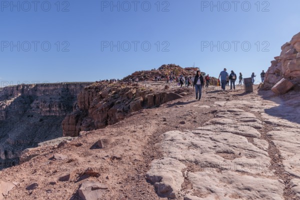 Tourists walk close to the edge of the canyon at Guano Point area of Grand Canyon West near Peach
