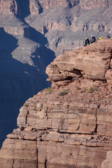 Visitors climb on rock formation rising above the canyon at Guano Point in Grand Canyon West near
