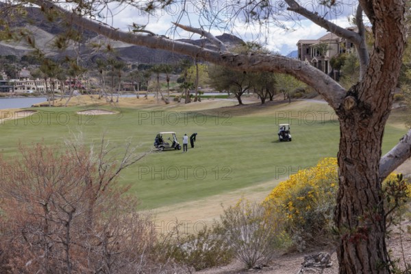 Golfers playing on a golf course along the shoreline of Las Vegas Wash at Lake Las Vegas in
