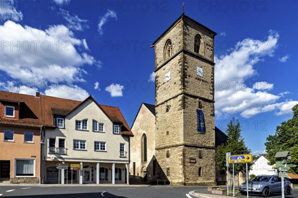 Central church tower in the village with surrounding buildings and streets under a blue sky, The