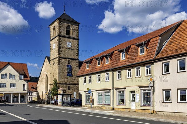 Church tower next to village buildings under a cloudy blue sky, The steeple of the Protestant
