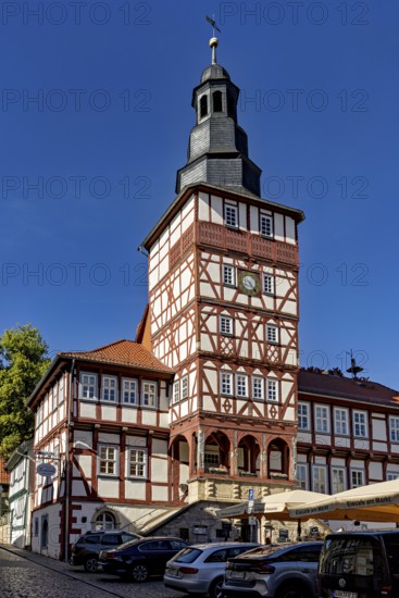 Half-timbered tower and historic buildings with parked cars under a blue sky, The town hall of