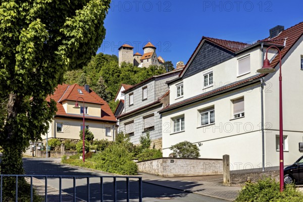 Rural houses on the roadside with a historic castle on the hill in the background, Normannstein