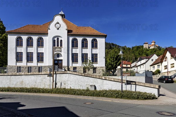 A white building with red tiled roofs in a small, quiet village under a blue sky, the town of